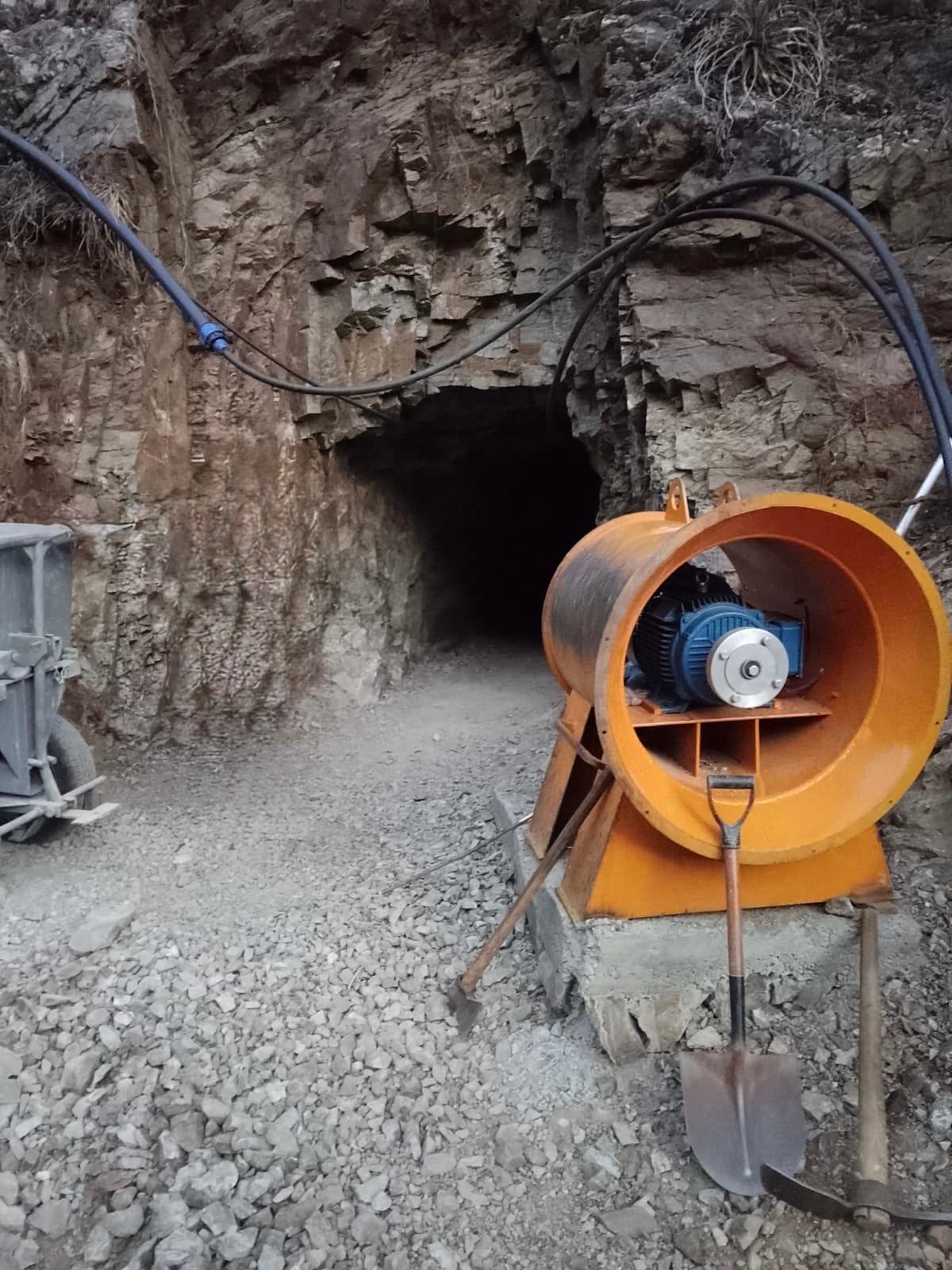 Ventilation fan and mine cart at the entrance to a small underground mine
